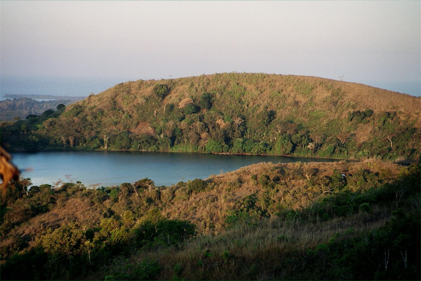 A sacred crater lake below a forested dome near Mont Passot